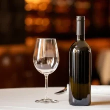 Cute-3D-render-of-a-wine-bottle-on-a-table-with-a-glass,-representing-corkage.