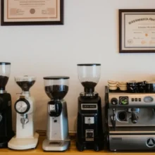 A-beautifully-arranged-modern-coffee-shop-interior,-featuring-an-espresso-machine,-coffee-grinders,-and-coffee-beans,-with-a-barista-certification-hanging-on-the-wall,-creating-a-warm-and-inviting-atmosphere.